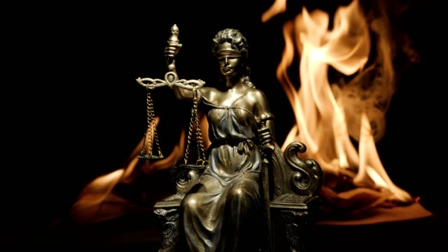 Statue-of-Lady-Justice-on-the-background-of-the-flame-of-a-burning-book