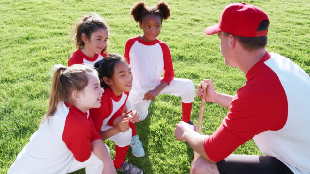 Equipo-de-béisbol-de-niñas-y-hombre-entrenador-tener-equipo-hablar