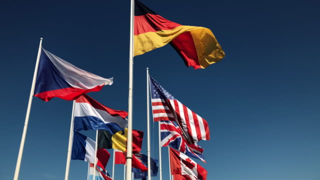 National-flags-together-flying-in-slow-motion-on-blue-sky-background