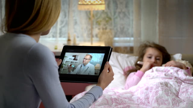 Mutter-mit-einer-kleinen-kranken-Tochter-bekommt-eine-ärztliche-Beratung-mit-video-Chat-zu-Hause.