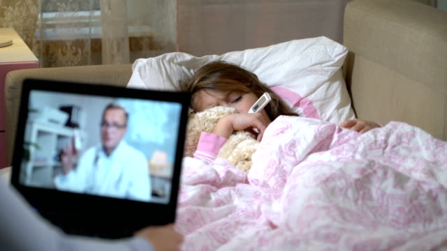 Mamá-con-una-hija-enferma-obtiene-la-consulta-de-un-doctor-utilizando-el-chat-de-video-en-casa.