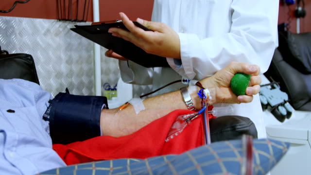 Médico-comprobar-a-senior-hombre-donar-sangre-4k