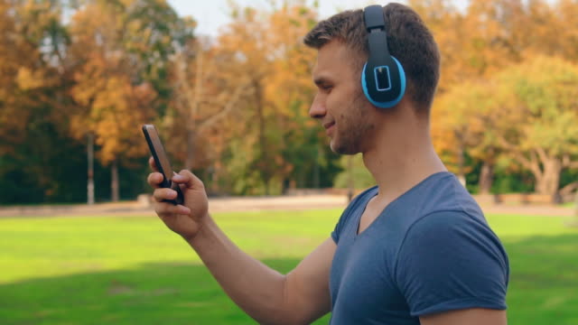handsome-man-with-earphones-walks-outdoors