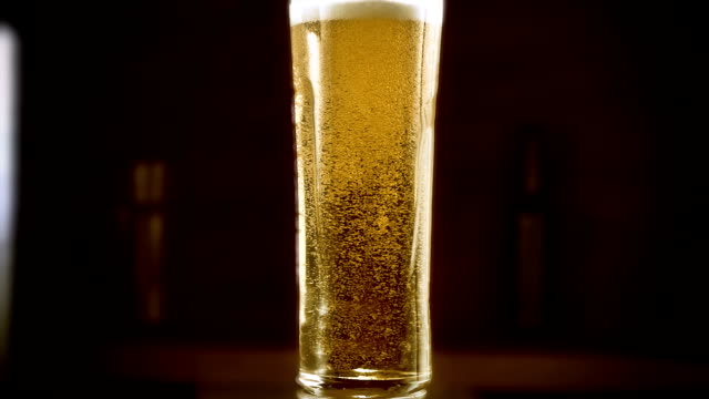 Close-up-Zeitlupen-Kaltlicht-Bier-in-einem-Glas-mit-Wasser-tropft-auf-bar-Hintergrund.-Craft-Bier-hautnah