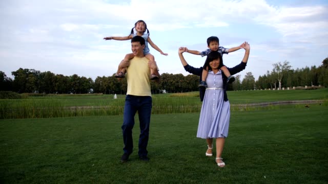 Fröhliche-asiatischen-Eltern,-die-Kinder-auf-den-Schultern-tragen