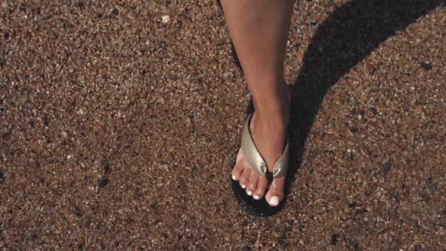 Woman's-feet-in-sandals-on-beach.