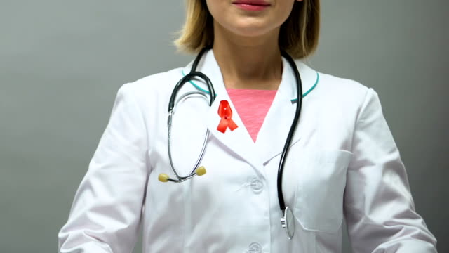 Woman-physician-with-red-ribbon-posing-for-camera,-AIDS-awareness,-sti-disease