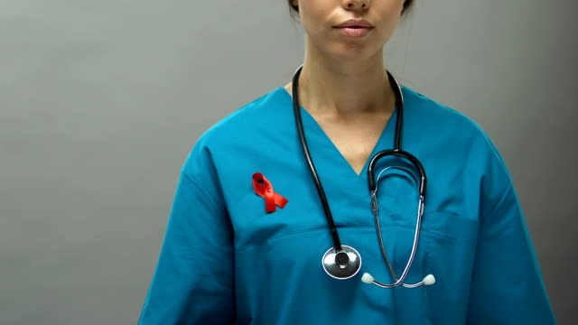 Serious-woman-physician-with-red-ribbon-supporting-AIDS-awareness-campaign