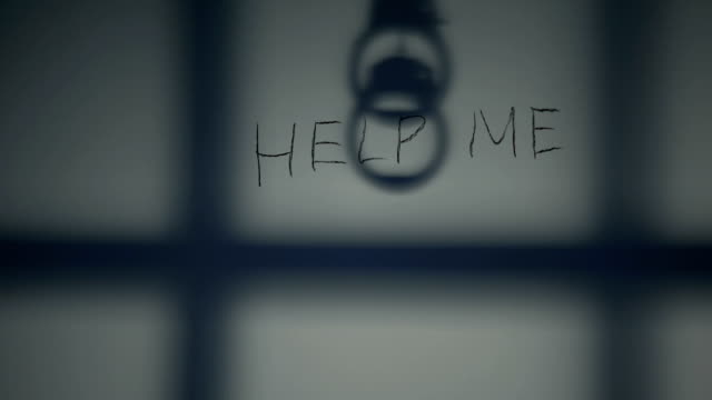 Help-me-phrase-written-on-prison-wall,-handcuffs-and-bars-shadow,-despair