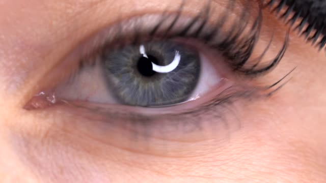 blue-eyed-woman-applying-mascara-closeup-macro