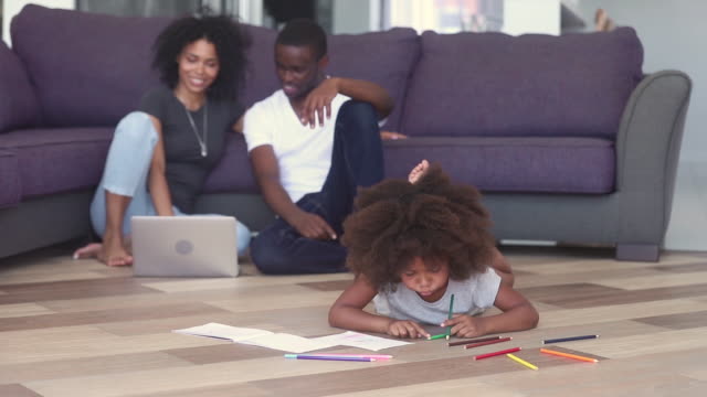 Kid-drawing-parents-using-notebook-spending-time-on-heated-floor