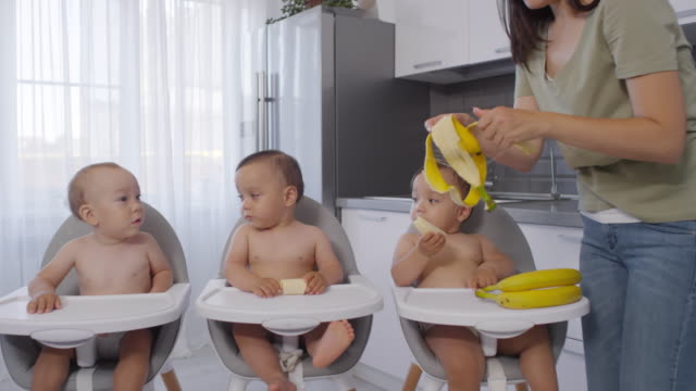 Mujer-asiática-Peeling-Bananas-para-trillizos-bebé-en-casa