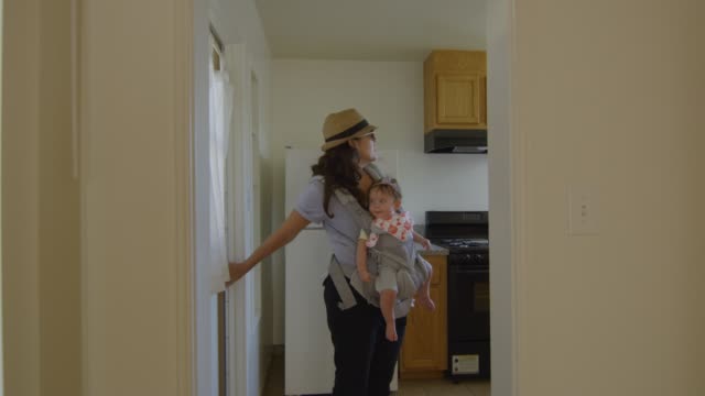 Frau-mit-Baby-schaut-sich-in-einer-leeren-Wohnung-um