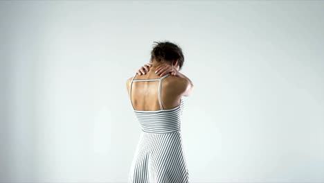 Young-female-with-neck-ache-rubbing-her-neck-against-light-background