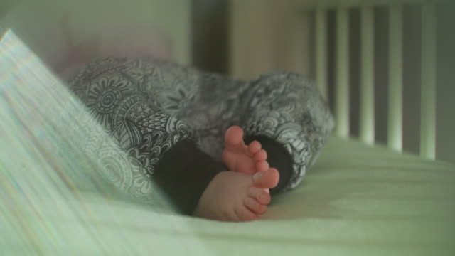 Flare-Babys-Füße-in-Hosen-schütteln-im-Bett-mit-Objektiv