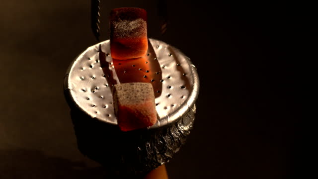 The-man-reads-the-red-hot-coals-on-the-bowl-for-the-hookah.