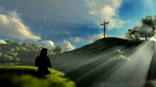 Woman-praying-at-Jesus-cross-against-beautiful-sun-rays,-panning