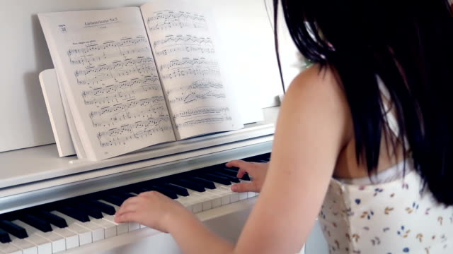 Young-brunette-woman-is-playing-the-piano-in-bright-room