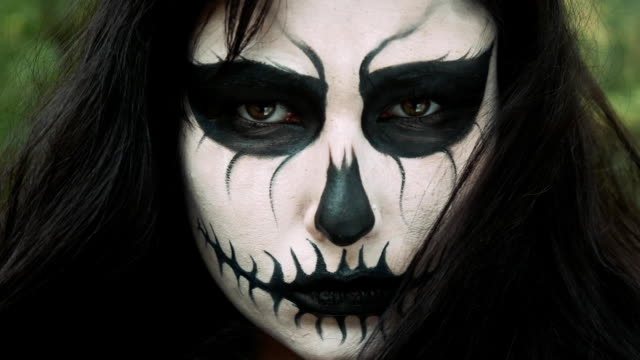 Young-woman-in-scary-black-and-white-halloween-make-up-looking-into-camera