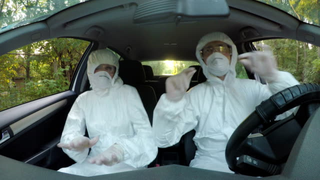 Funny-concept-of-two-young-hazmat-scientists-workers-in-car-dancing-and-driving-to-contaminated-location