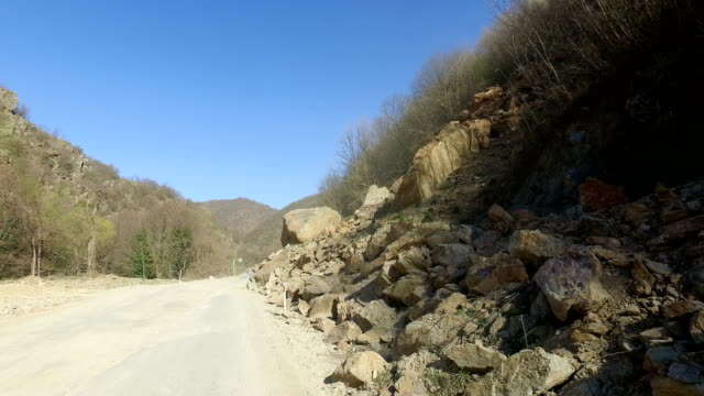 road-is-blocked-by-a-land-slide-of-rock-and-debris-to-where-it-is-a-hazard-for-drivers-in-cars
