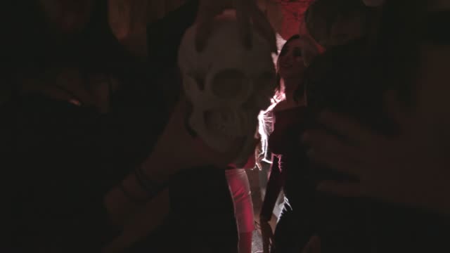 Young-vampire-woman-holding-skull-and-dancing-at-Halloween-party
