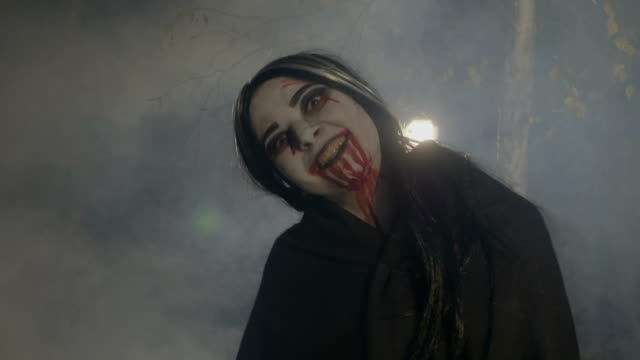 Bloody-evil-female-vampire-enjoying-the-foggy-halloween-night-in-the-woods-and-laughing