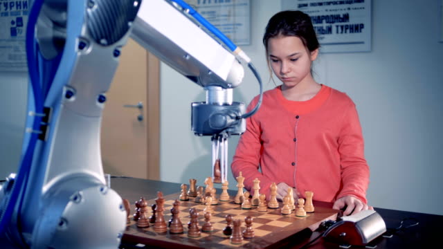 Junges-Mädchen-spielt-Schach-mit-einem-modernen-automatisierten-Schach-Roboter.-Kind-Genie-Konzept.-4K.