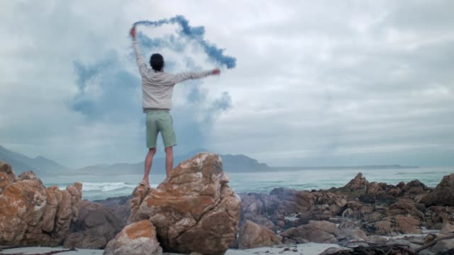 Man-playing-with-colour-smoke-grenade-at-the-beach