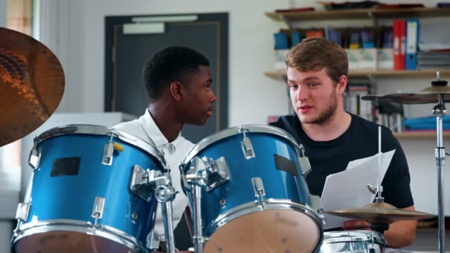 Männliche-Schüler-mit-Lehrer-im-Musikunterricht-Schlagzeug-spielen