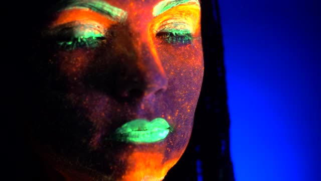 Close-up-portrait-of-fashion-model-woman-with-braids-in-neon-light.-Fluorescent-makeup-glowing-under-UV-black-light.-Night-club,-party,-halloween-psychedelic-concepts