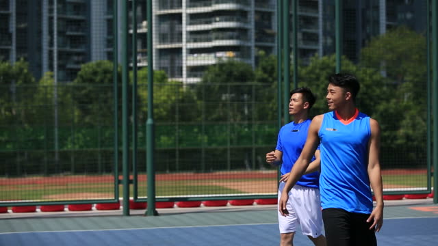 adultos-jóvenes-asiáticos-jugando-baloncesto-en-la-cancha-al-aire-libre