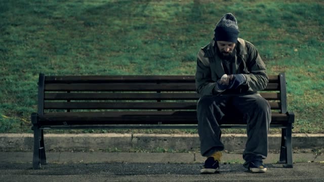 Lonely-beggar-on-bench-cheking-his-money