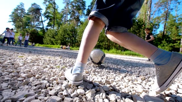Grupo-de-adolescentes-corriendo-tras-la-pelota-jugando-al-fútbol-de-yarda-en-día-de-verano-en-el-Parque