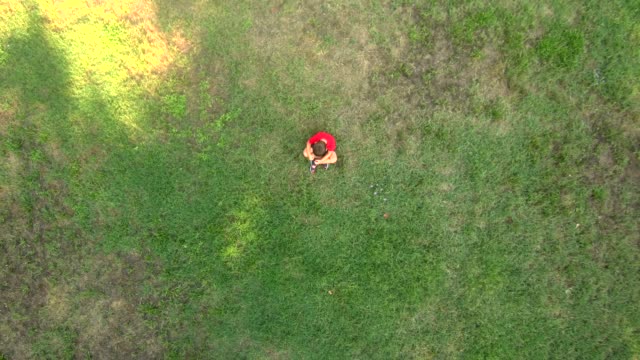 Little-boy-seated-alone-on-the-middle-of-a-field.-Sadness-concept.-Aerial-view.