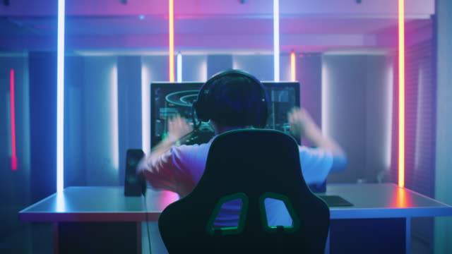 Professional-Gamer-Playing-and-Winning-in-First-Person-Shooter-Online-Video-Game-on-His-Personal-Computer.-Footage-Fade-out-into-Bokeh.-Room-Lit-by-Neon-Lights-in-Retro-Arcade-Style.-Cyber-Sport-Championship.