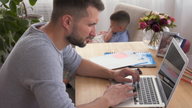 Focused-dad-working-and-babysitting-with-children