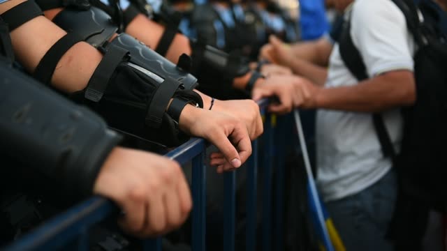 Polizist-die-Hände-auf-einen-Sicherheitszaun-während-eines-Aufstandes