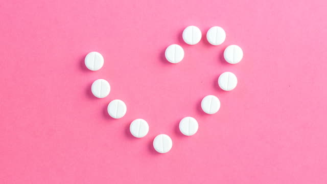 Corazón-en-forma-de-comprimidos-blancos-sobre-fondo-rosa
