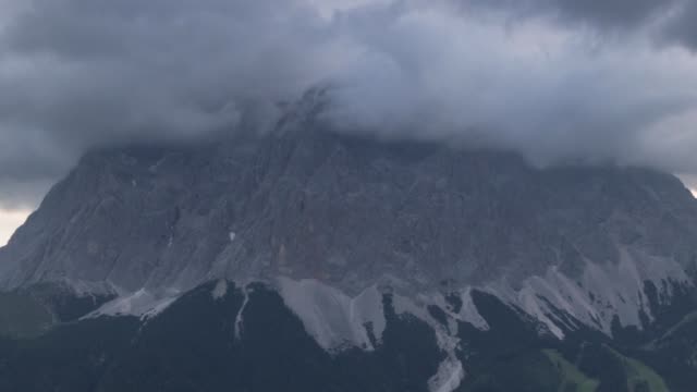 Lapso-de-tiempo-de-las-nubes-de-trueno-oscuro-pasando-por-montaña-Zugspitze-en-Alemania-Alpes-de-Baviera,-junto-a-la-naturaleza-de-tormenta-de-paisaje-Ehrwald-pueblo-senderismo