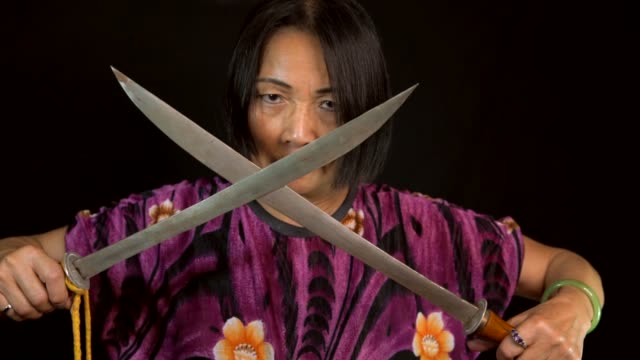 alten-einschüchternd-Asiatin-kreuzt-die-Schwerter-mit-schwarzem-Hintergrund