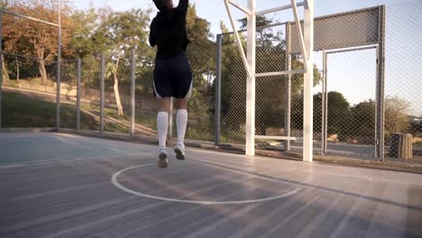 Close-up-footage-of-a-female-athlete-legs-in-white-golf-socks-and-sneakers.-Female-baasketball-player-bouncing-ball-from-hand-to-hand-then-make-a-shot.-Sun-shines-on-the-background
