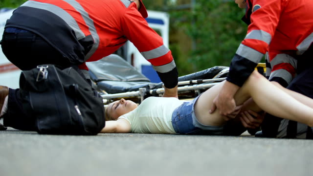 Ambulance-service-staff-taking-unconscious-girl-to-ambulance,-using-stretcher