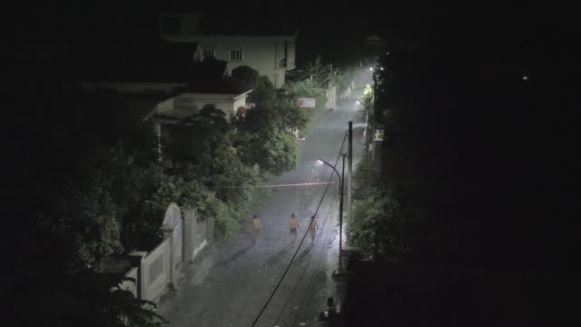 Silhouetten-der-Männer-zu-Fuß-in-kleinen-Straße-in-der-Nacht,-während-es-regnet