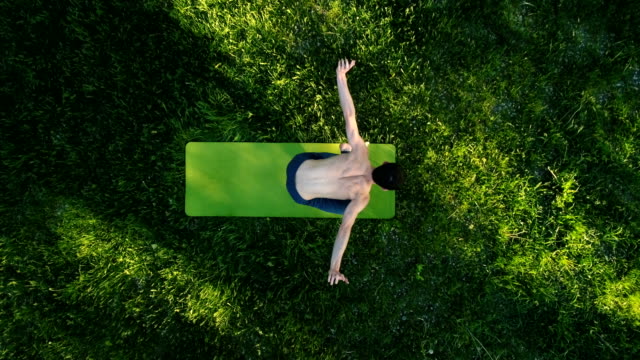 Professionelle-Yoga-Kerl-praktizieren-Yoga-im-Park.-Ansicht-von-oben.-Drohne-Filmmaterial.