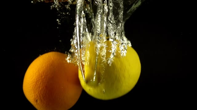 Von-einer-Zitrone-und-Orange-in-Wasser-fallen.-Slow-Motion.