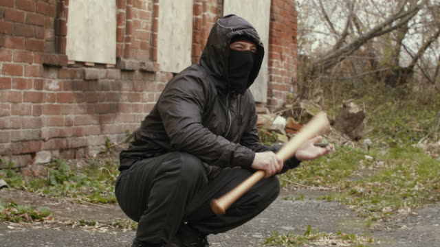 Masked-bandit-with-baseball-bat-at-abandoned-place.