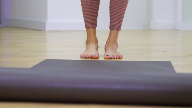 closeup-view-of-young-woman-feet-unrolling-mat-and-stepping-on-it-preparing-for-training