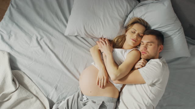 Glückliche-junge-Paar-schlafen-zusammen-im-Bett,-Sweet-liebevolle-junge-Menschen-halten-einander-während-Sie-schlafen.-Schöne-Frau-ist-schwanger,-liebevolle-Partner-unterstützt-ihr-von-da-zu-sein-für-sie.