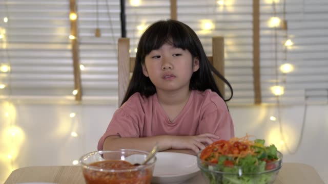 Asiatische-Kindermädchen-warten-Vater-und-Mutter-kommen-nach-Hause-Geburtstagsfeier-und-Abendessen-zusammen.-Unglückliche-Familienzeit-zu-Hause.-Konzept-von-einsam,-enttäuscht-und-traurig.